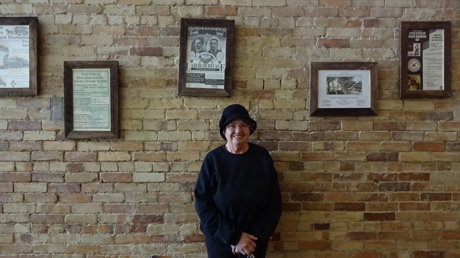 Cheryl Blosser pictured in the Tecumseh Theater amongst past Little Cities of Black Diamonds Day posters