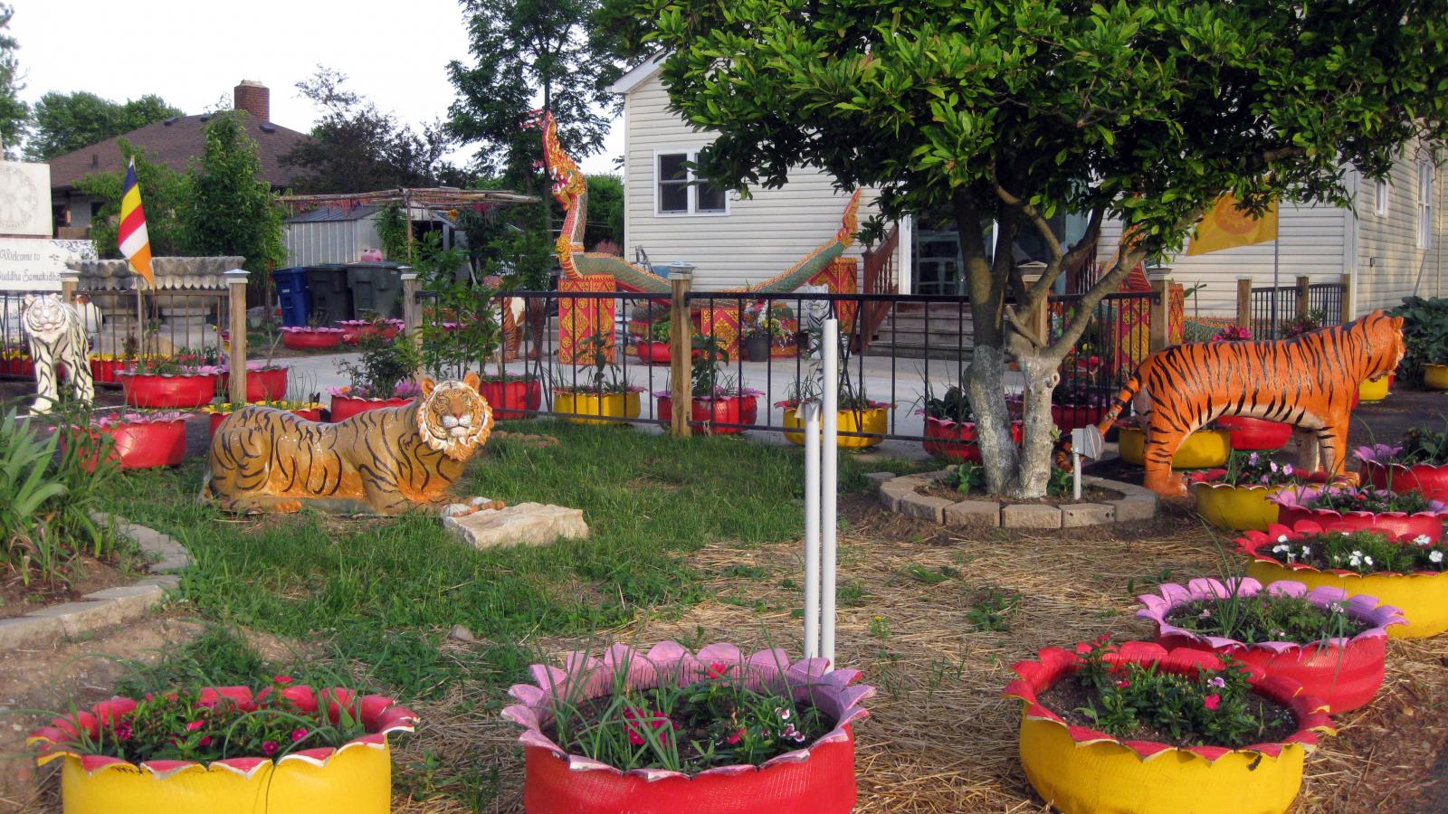 The yard outside the home/temple is elaborately decorated with painted concrete animals and colorful up-cycled tire planters, all of which were created by the various monks that have lived in Wat Buddhasamakidham.