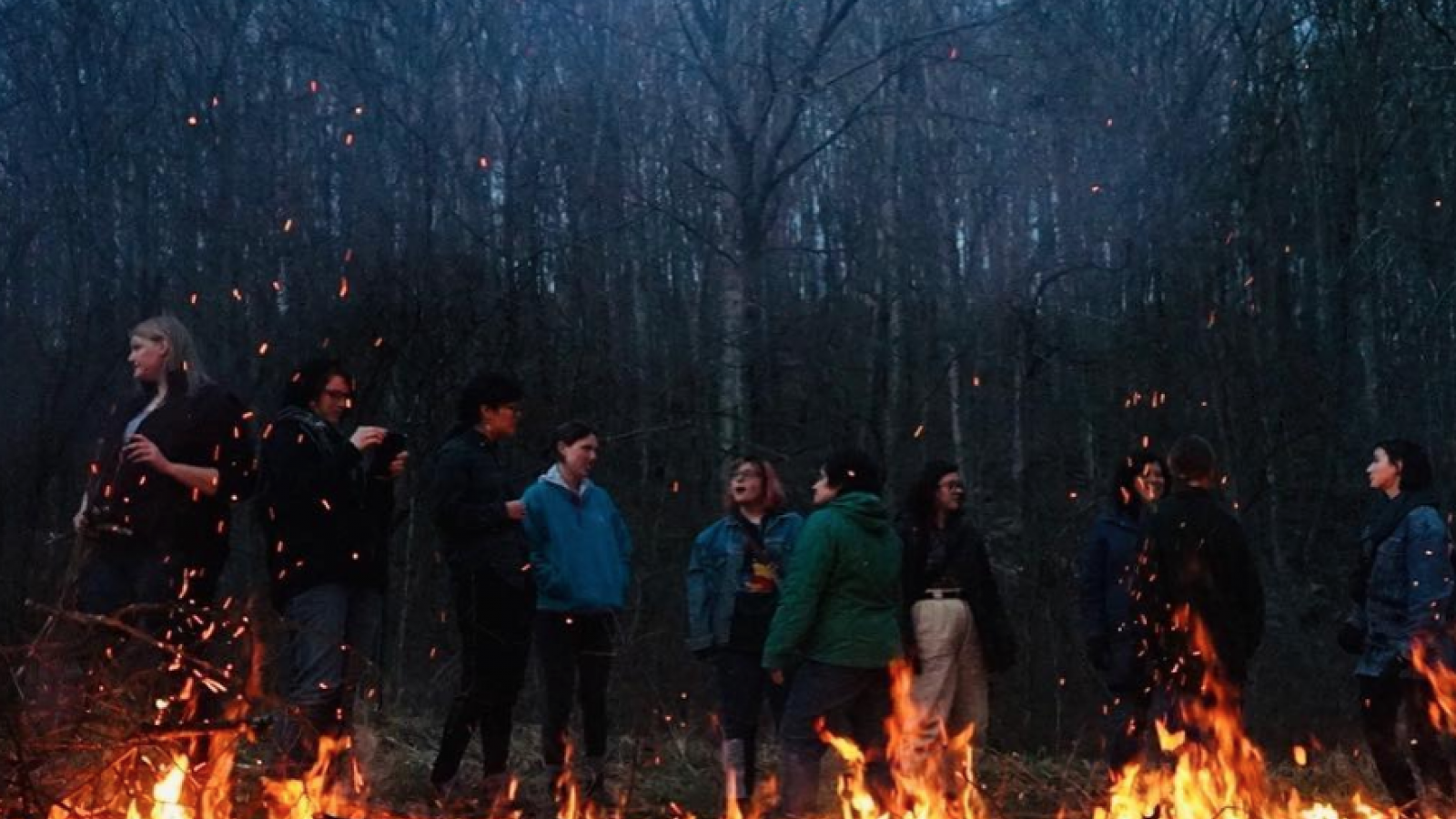 Image of field school students standing behind a fire in the woods
