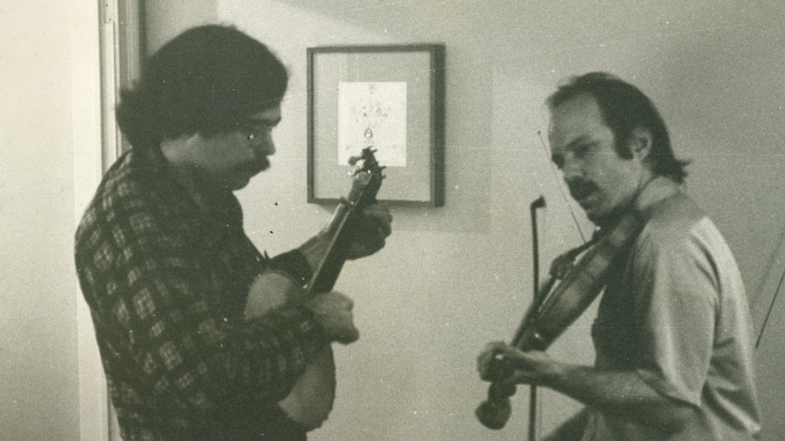 Unger playing banjo in living room with an unknown man, 1973