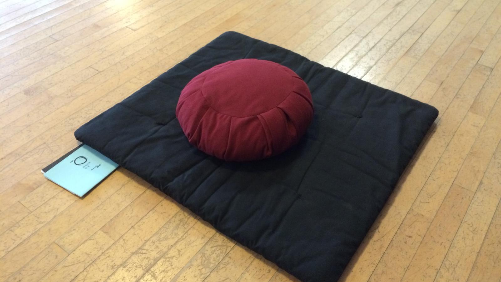 A typical meditation zabuton (mat) with a zafu (cushion), along with the sutra books
