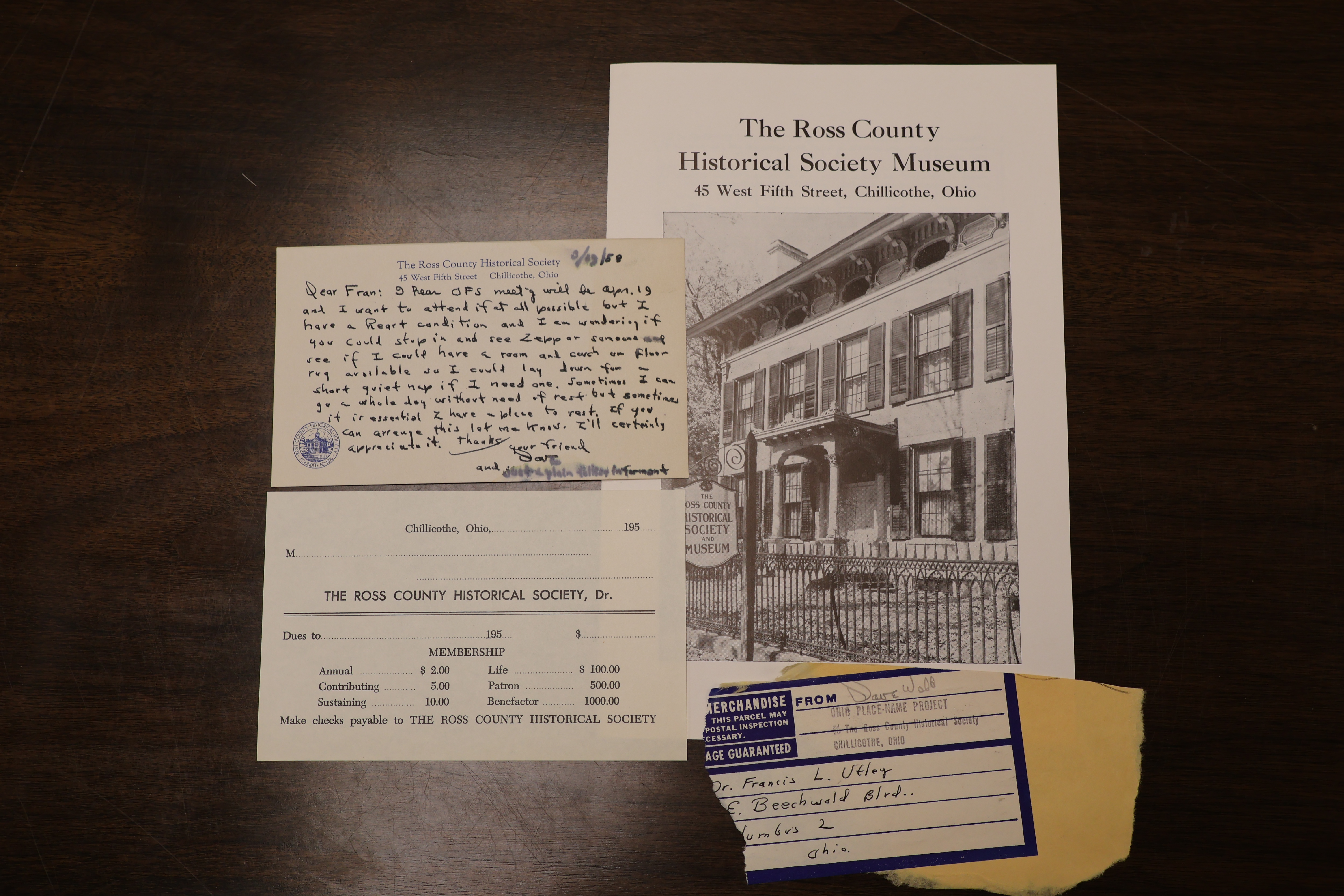 Displayed are four items from the collection. The first is a brochure on the Ross County Historical Society. The second is a ripped portion of a postal address for correspondence between Dave Webb and Fran Utley. The third is a membership card for the Ross County Historical Society. The fourth is a note from Dave to Fran about an accessibility request.