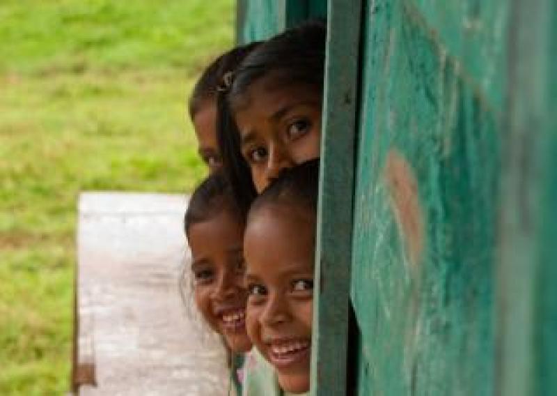 Central American kids leaning out of a window smiling