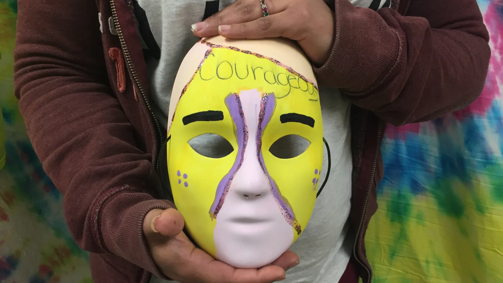 Close-up picture of Kaylena's art therapy mask as she holds it. 