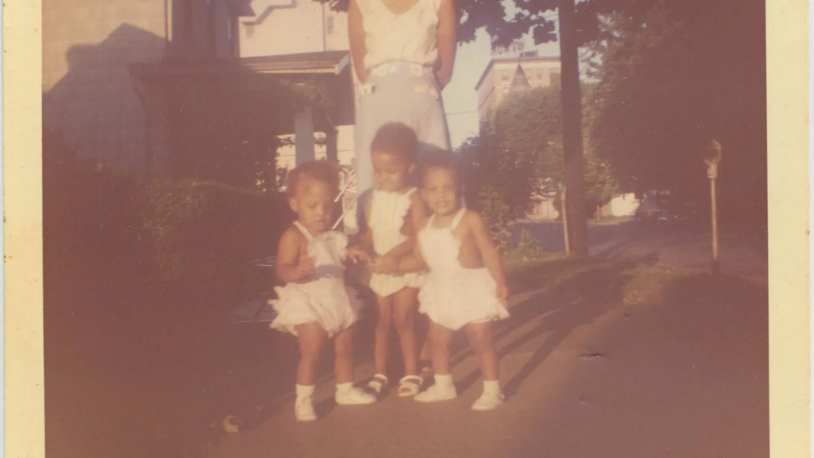 Jennie, Maureen, and Marlene as toddlers with mother Geraldine behind them standing on the sidewalk in front of 709 3rd Street