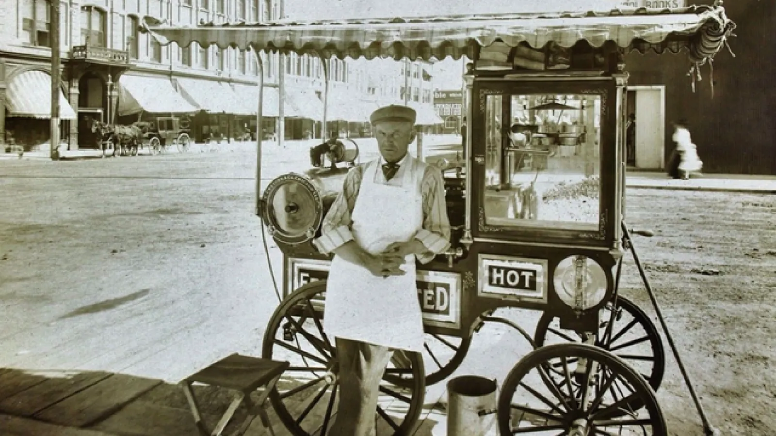 Generic lack-and-white photo of a man standing in front of a popcorn cart.