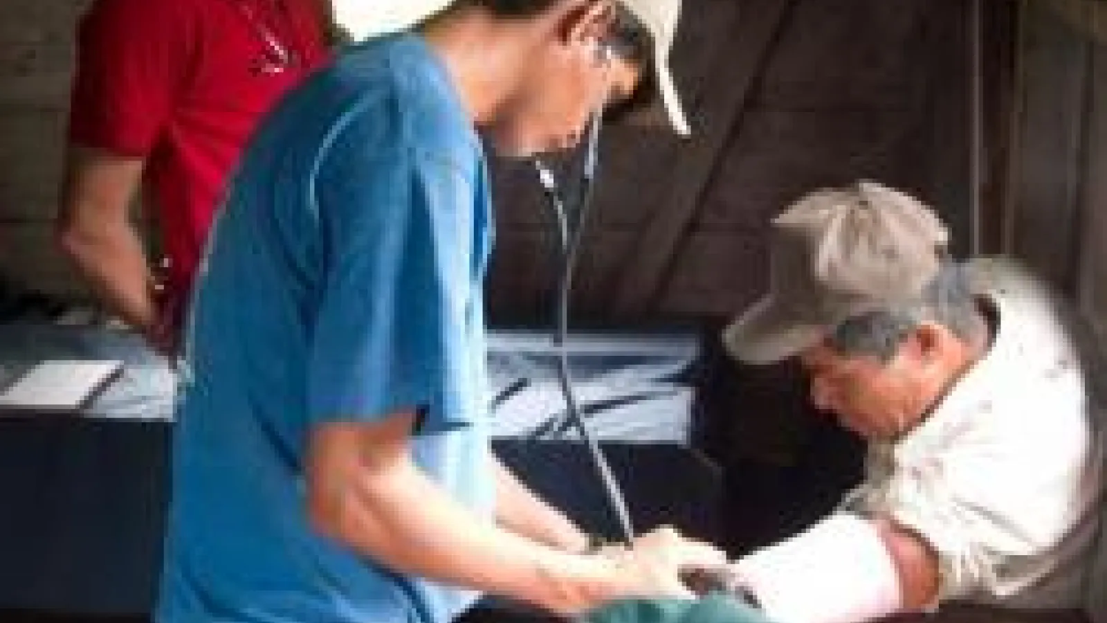 Health-care worker checking pulse on male patient's arm with a stethoscope