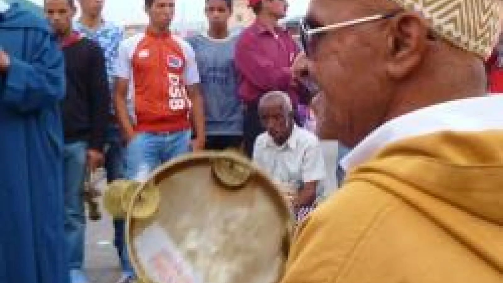 Master comedian Abdelhakim playing tambourine in front of group