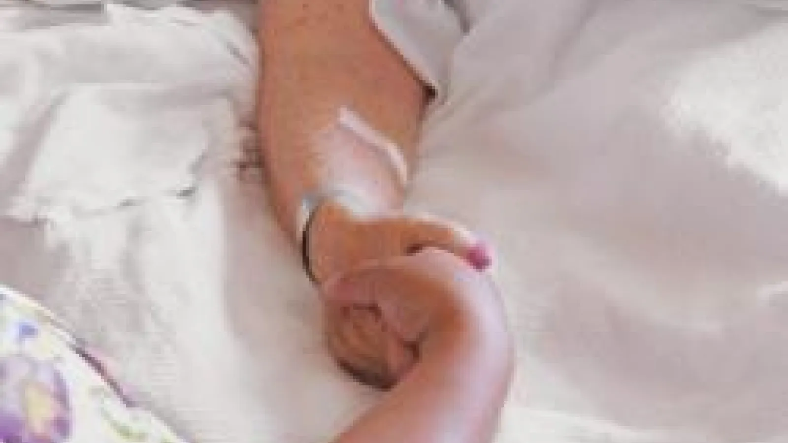 Elderly hospital patient holding hand of nurse