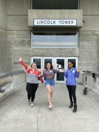 RAs Nicole Neifert, Kaylee Miller, and Ruth Tadese stand in front of Lincoln Tower's main entrance