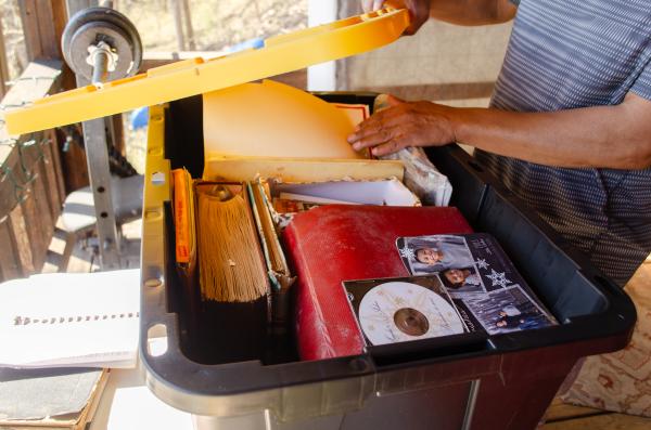 Hands dig through a plastic box of archival materials