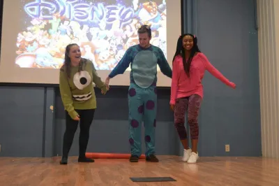 Three young people in Monsters, Inc. costumes on a stage