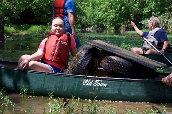 young volunteer with Friends of Scioto Brush Creek canoe with trash extracted from Creek