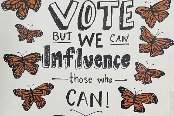 Protest sign with butterflies and "We may  not be able to vote but we can influence those who can"