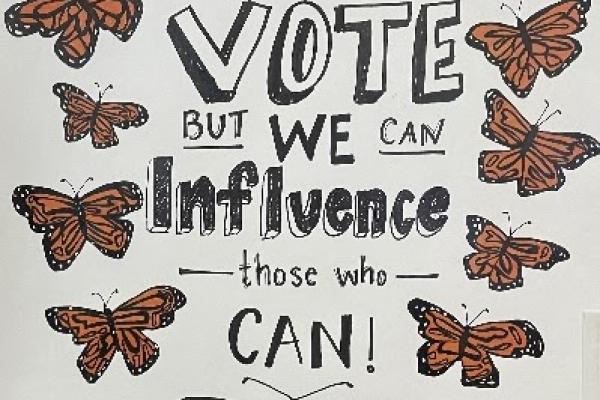 Protest sign with butterflies and "We may not be able to vote but we can influence those who can"