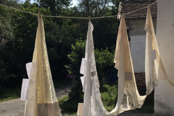 Lace shawls hanging on a line with paper attached to them