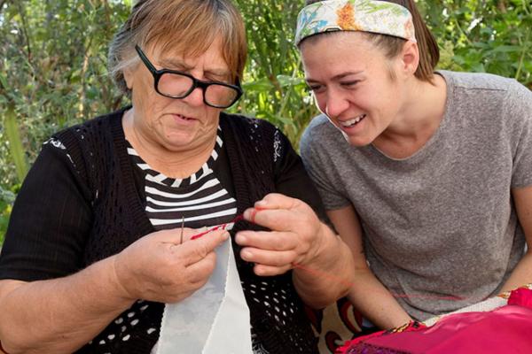 Sarah Craycraft closely watches Tsvetana Todorova working on her needlecraft in Bulgaria.