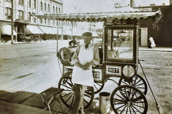 Generic lack-and-white photo of a man standing in front of a popcorn cart.
