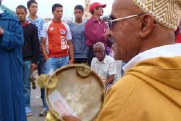 Master comedian Abdelhakim playing tambourine in front of group
