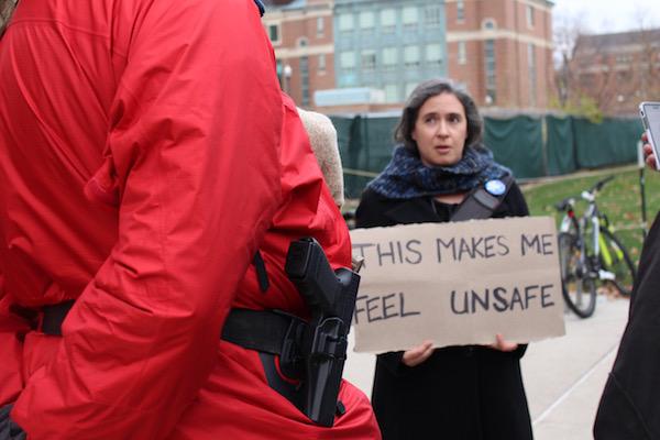 Merrill Kaplan holds a sign saying, "This makes me feel unsafe"