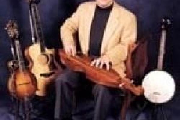 Hank Arbaugh sitting amongst five string instruments