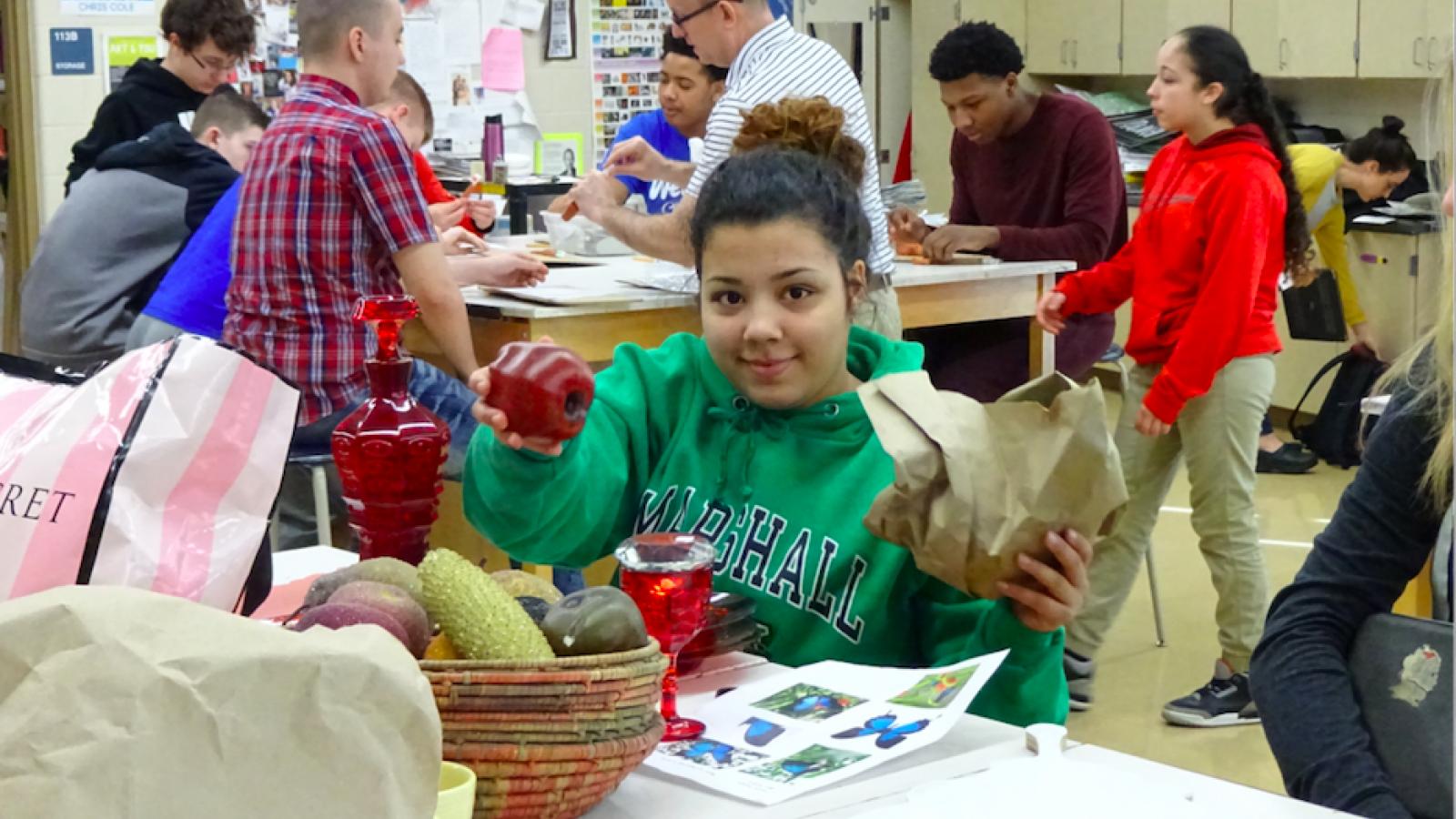 Student holding up the found objects she will use to decorate her butterfly. 