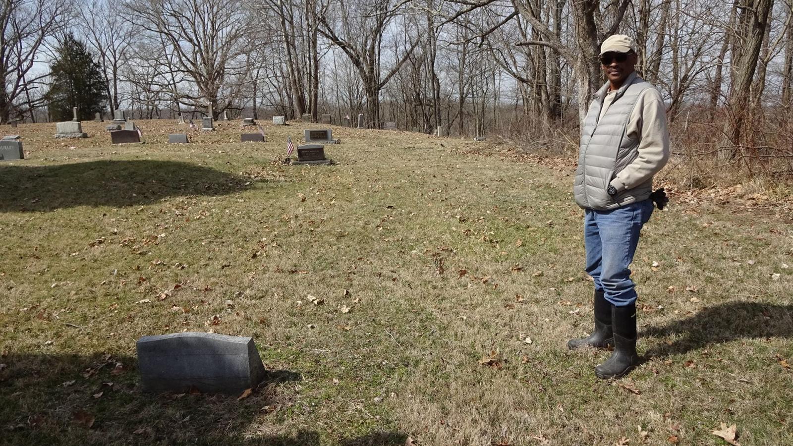 Harry Ivory stands next to his family's headstones.