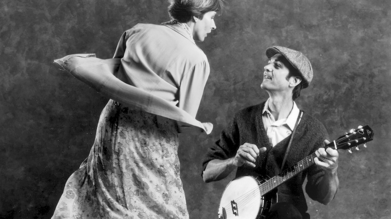 Rick Good on one knee playing banjo while woman dances