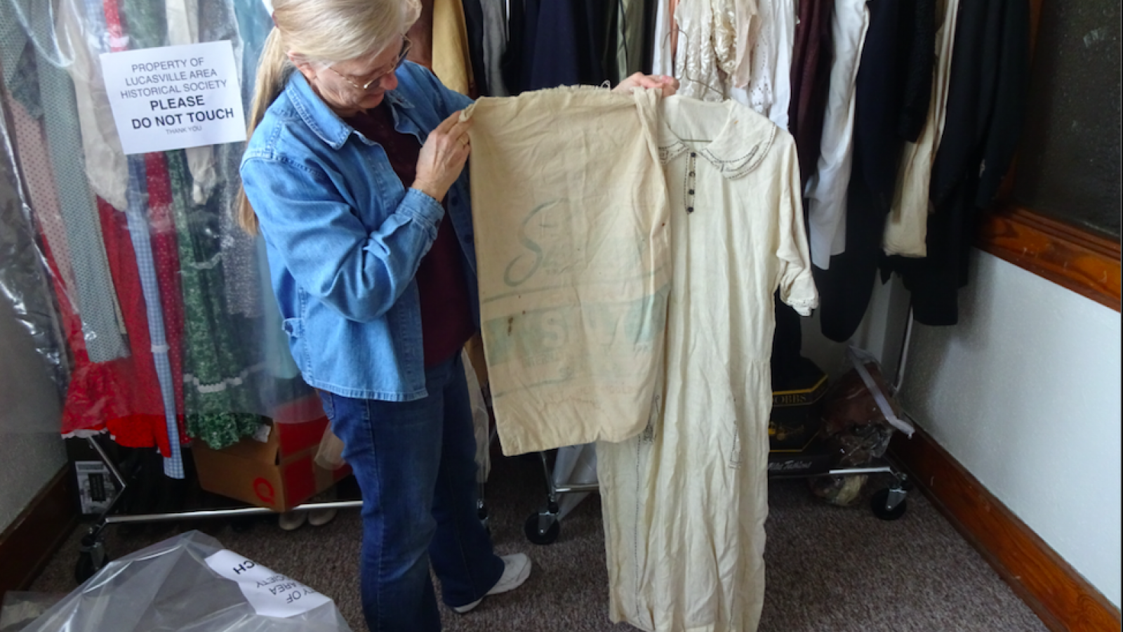 Pat Smith showcasing a flower-sack dress from the Historical Society’s collection of antique clothing. 