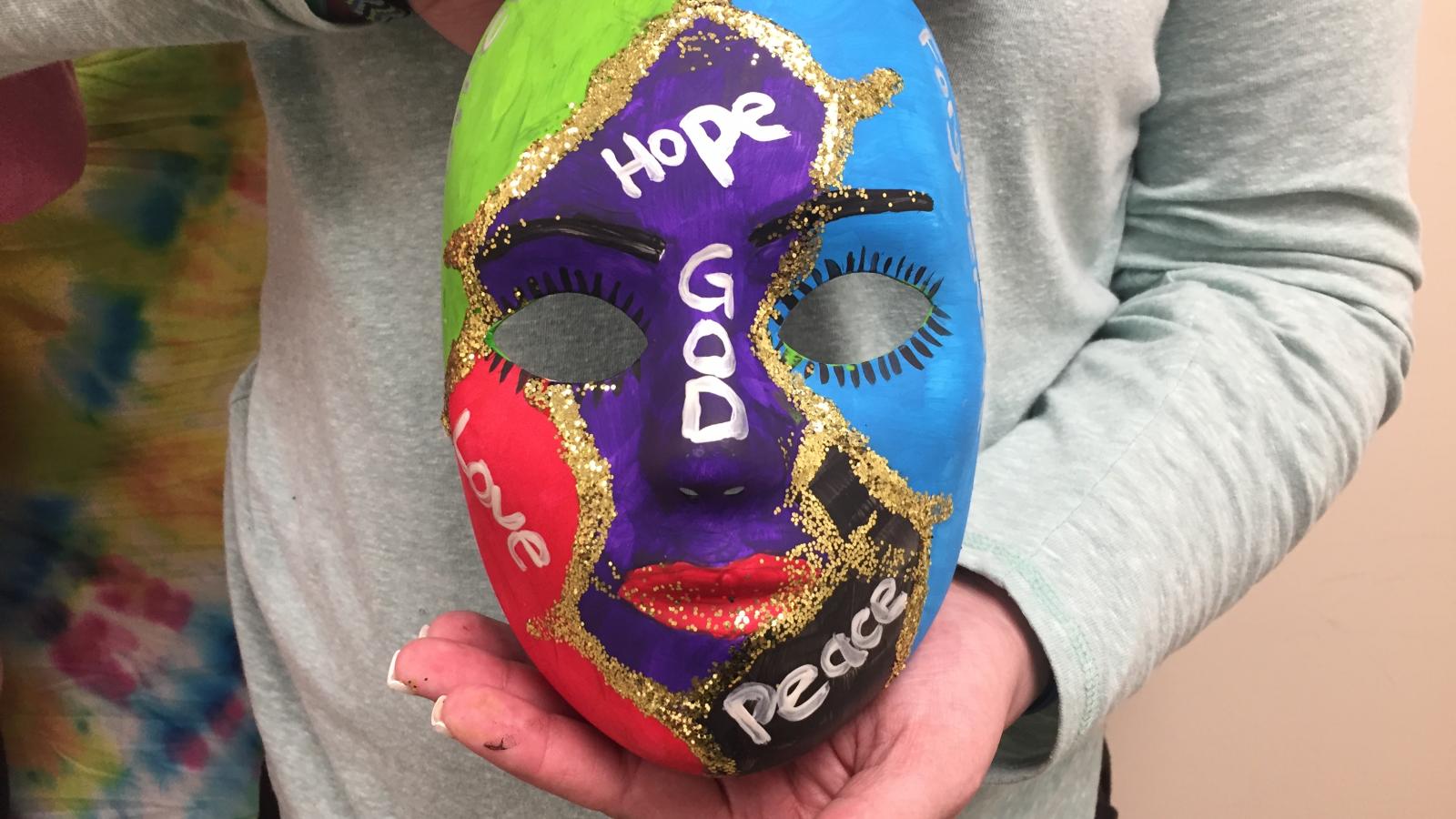 Close-up picture of Tabi's art therapy mask as she holds it.