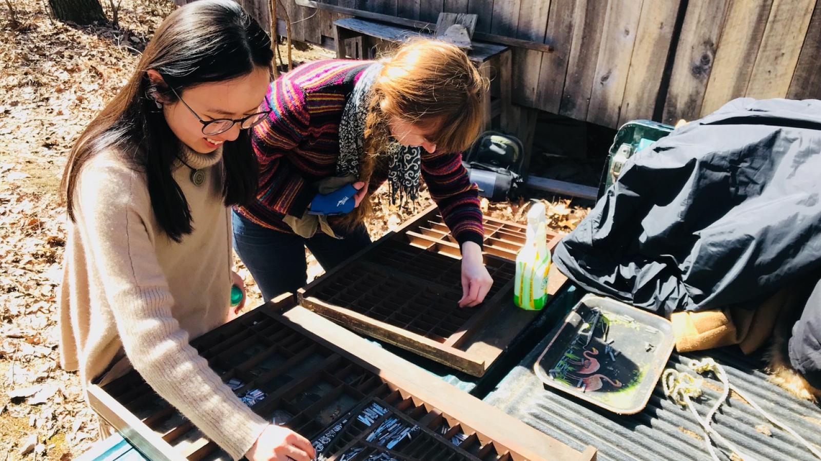 Luna Luo (left) and Molly Rideout (right) cleaning print type out of the back of Brian Richards's truck.