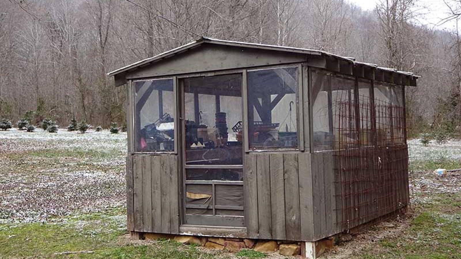 A brown wooden shed with screened in windows built by Ronny for his wife Cyndy.